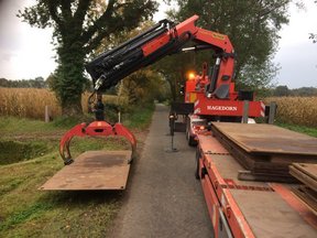 LKW Ladekran verlegt Stahlbleche als mobile Fahrstraße und tragfähigen Boden